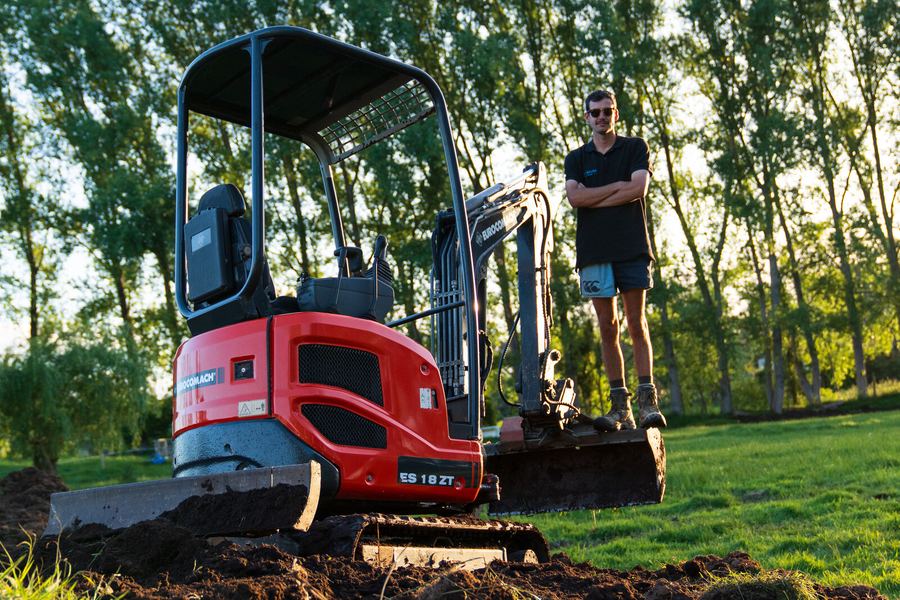 Max Arnel, owner of Maximum Earthworks, standing beside his excavator